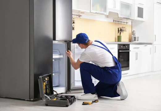 Technician crouching at an open bottom freezer compartment