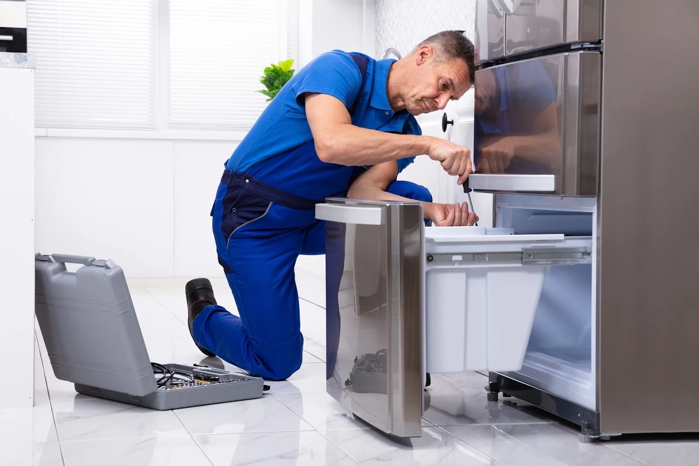 Technician using a screwdriver to repair an open refrigerator drawer