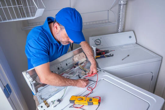 Technician using a multimeter to diagnose a laundry appliance control panel