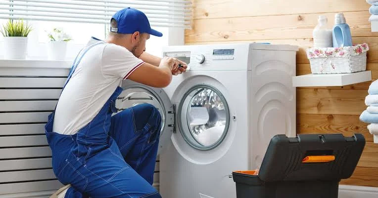 Technician working on washing machine controls in a home laundry room